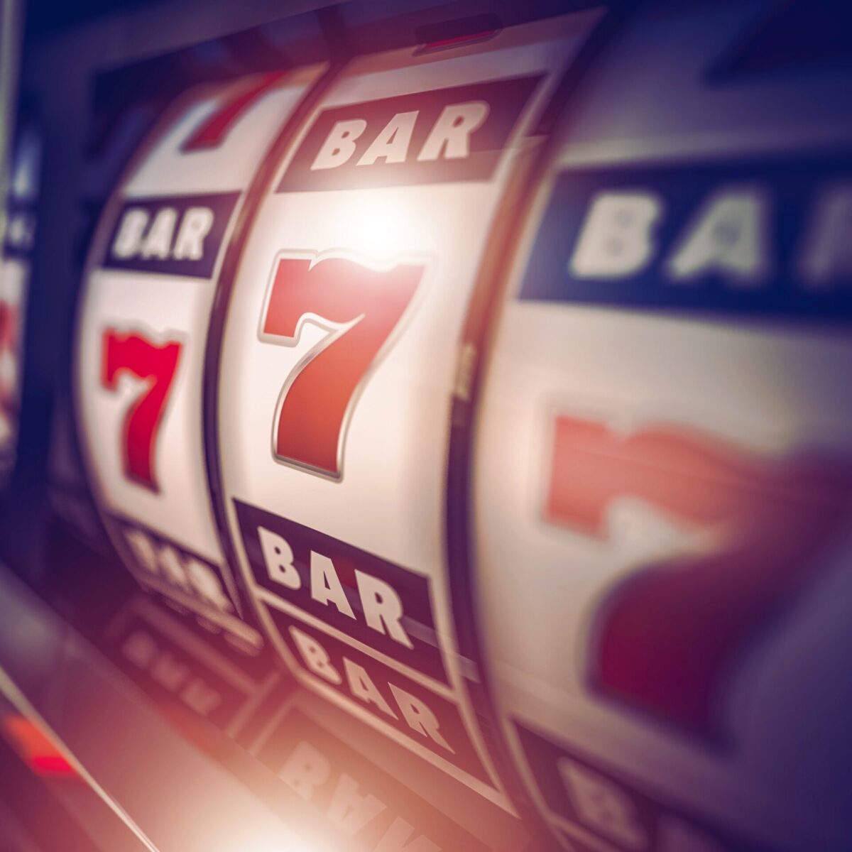 Close-up of a slot machine displaying a winning combination of red sevens and BAR symbols on the reels.